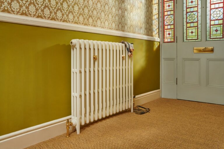 A Mercury 3 column cast iron radiator in Farrow and Ball paint with unlacquered brass TRV valves featured in a hallway.